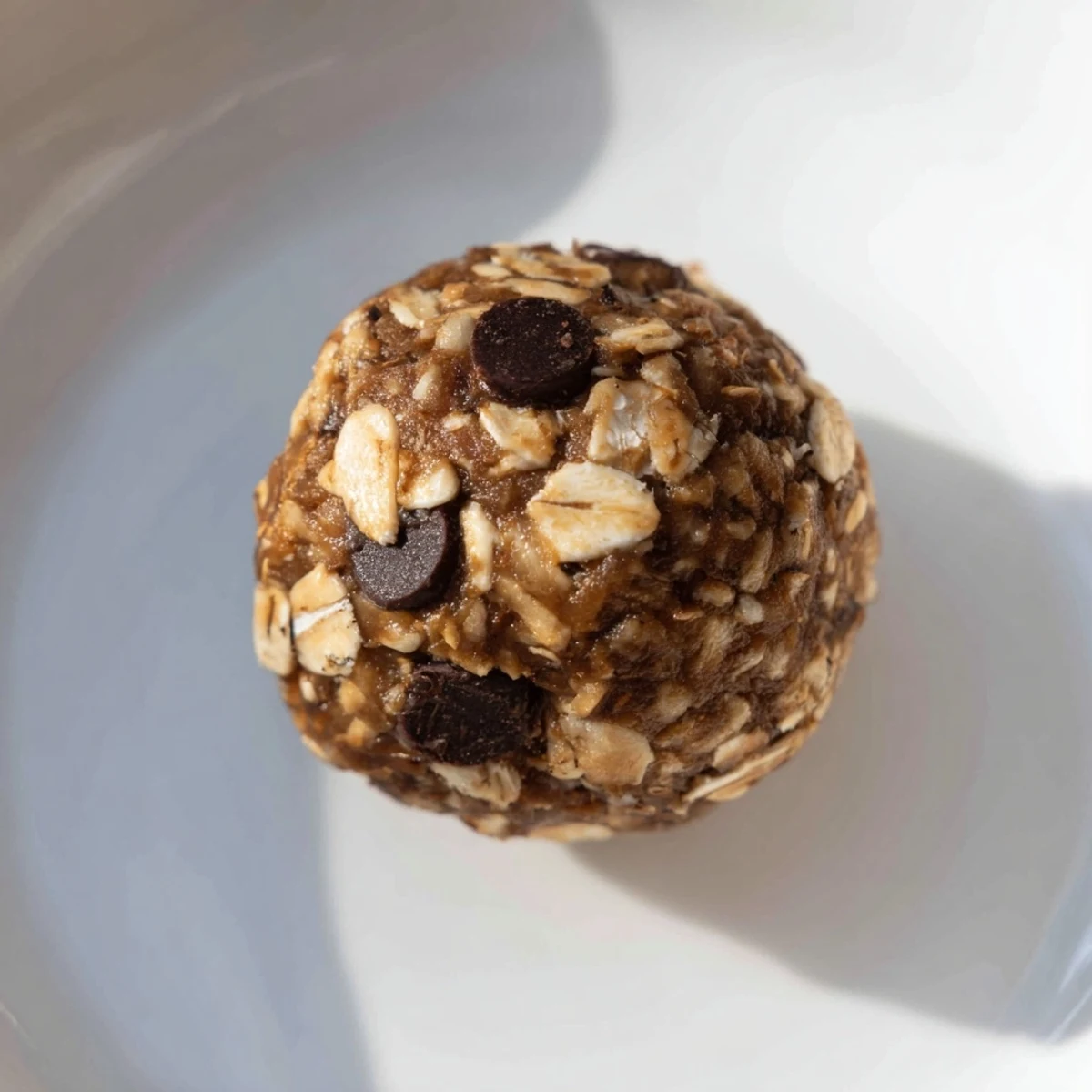 Homemade Chocolate Peanut Butter Energy Balls in a jar, with a rustic wooden spoon ready for serving at a healthy party.