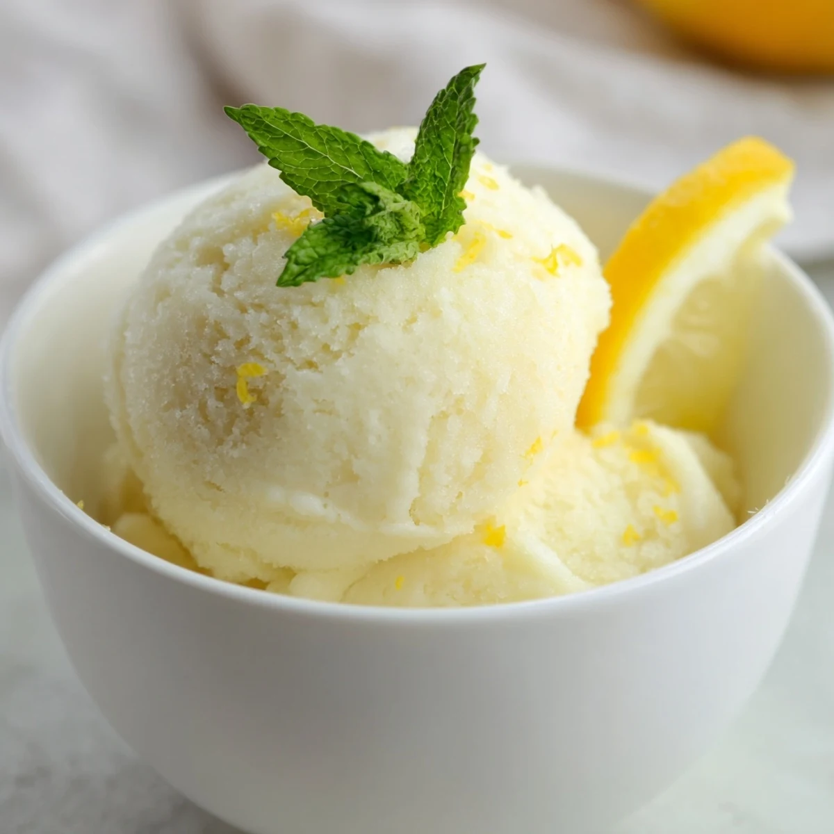 Chilled Lemonade Sorbet with Mint served in clear glasses, topped with fresh mint leaves for a refreshing summer treat.