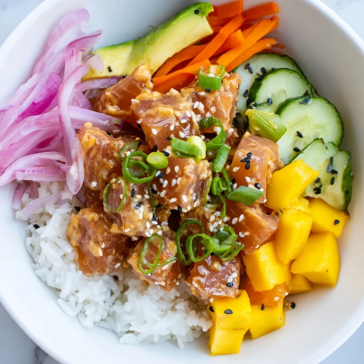 A close-up of a spicy tuna poke bowl with mango, featuring diced tuna and mango cubes atop sushi rice with cucumber and avocado slices.