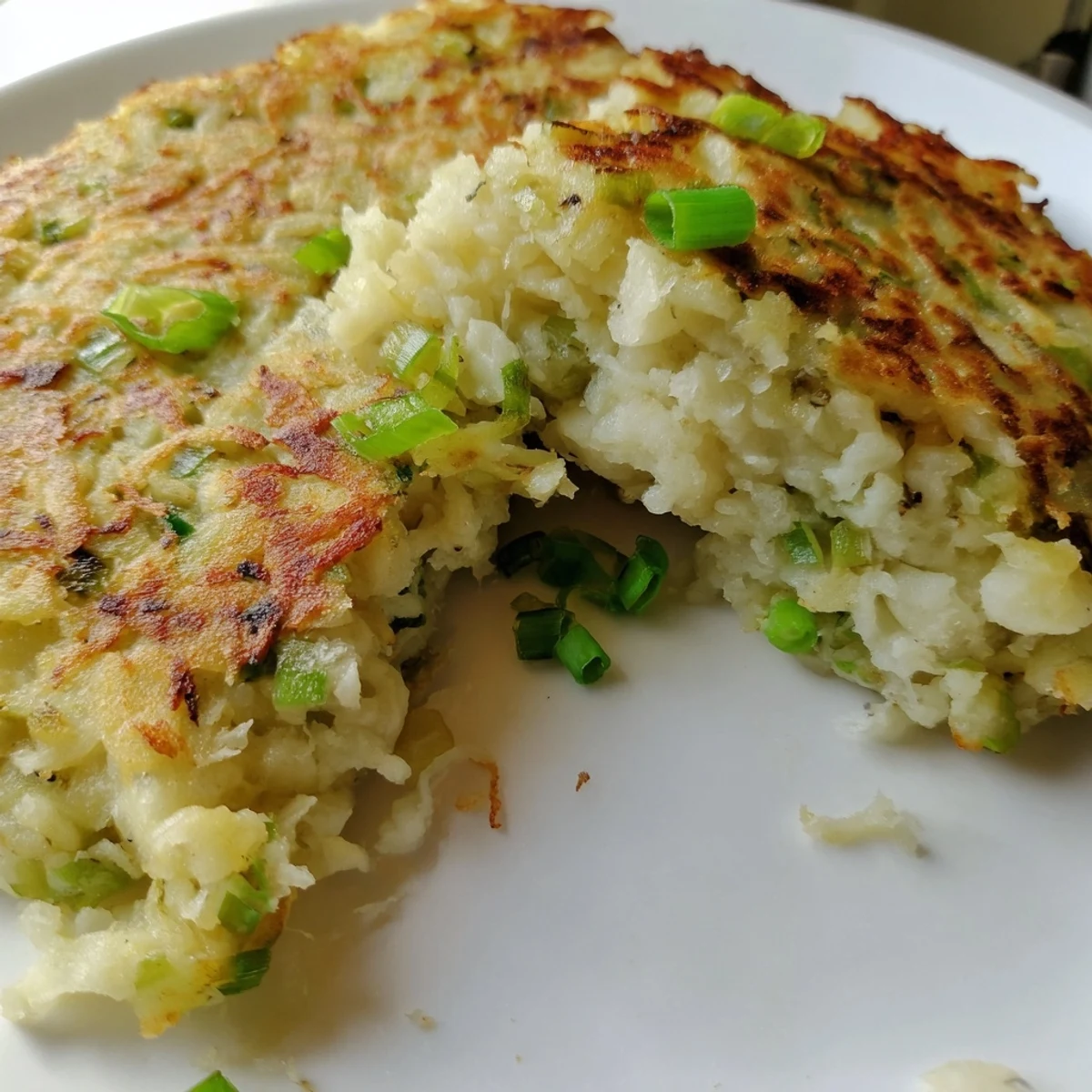 Freshly fried Irish Boxty Potato Pancakes with Scallions stacked high, garnished with chives and sour cream.