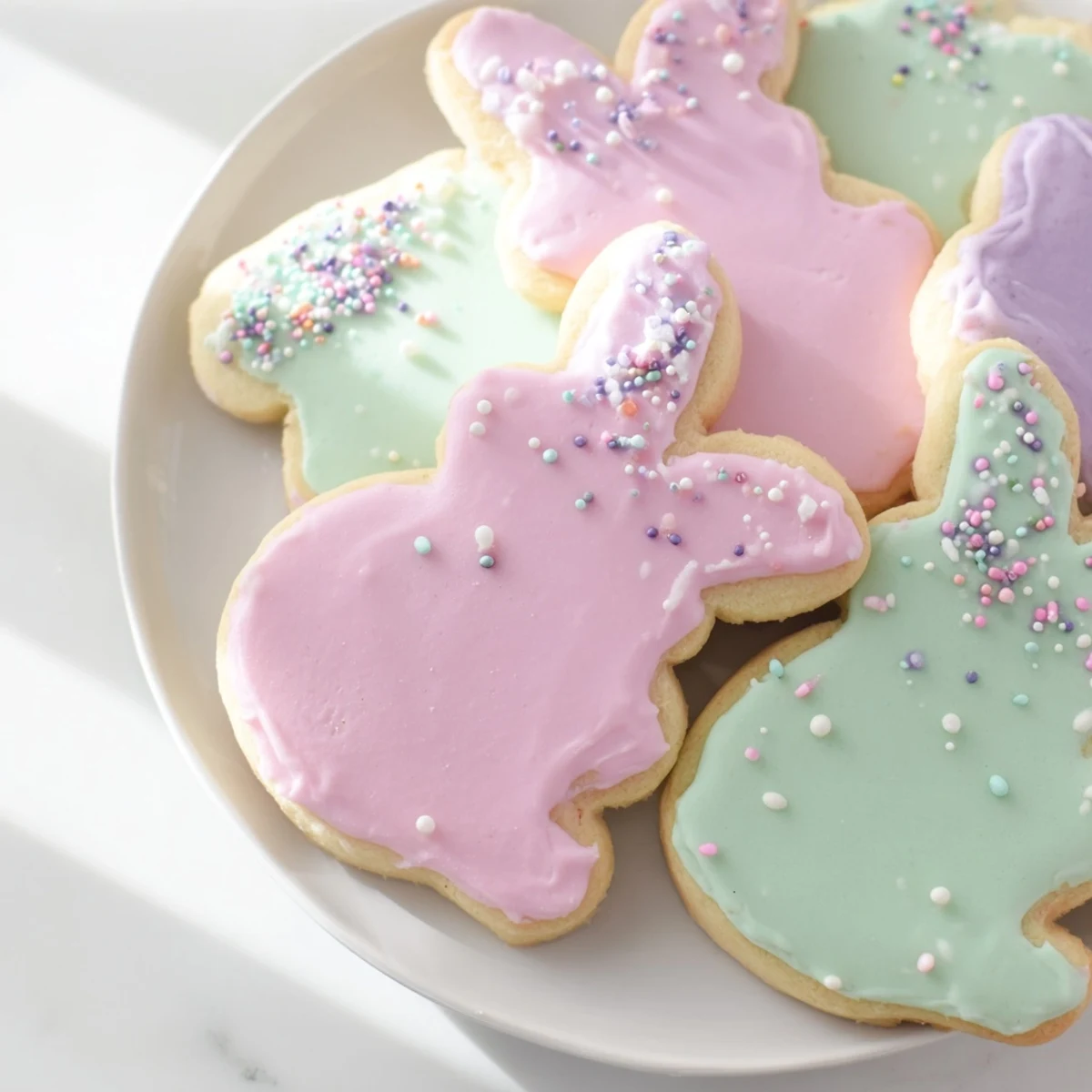 This image shows freshly baked Easter Bunny Sugar Cookies decorated with white icing, ideal for an easy family baking activity.