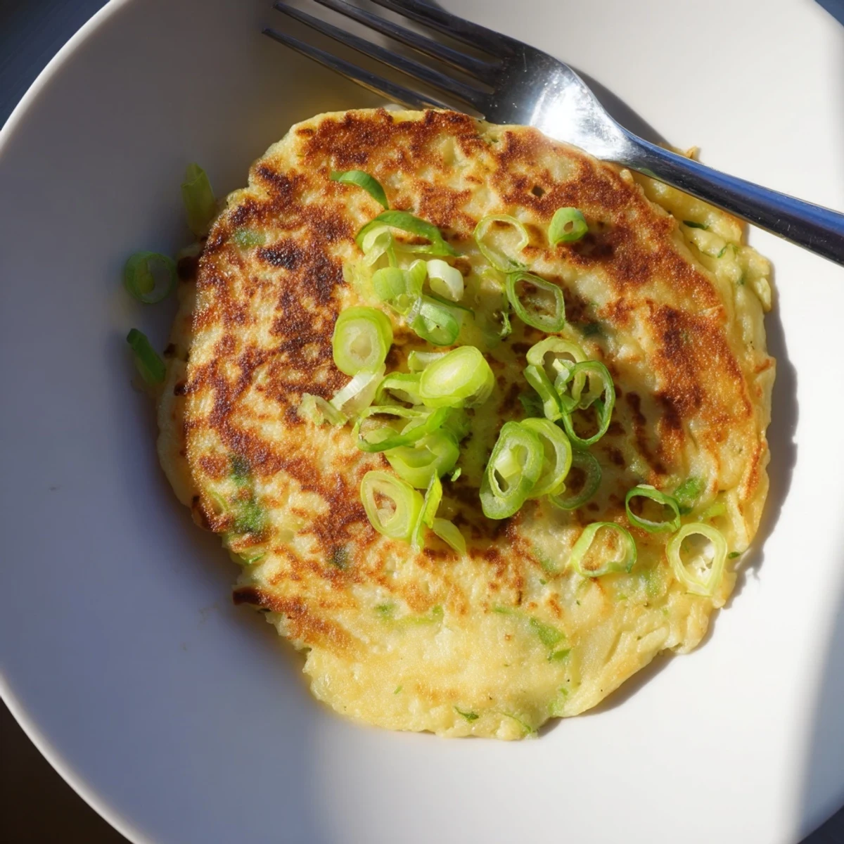 Golden-brown Irish Boxty Potato Pancakes with Scallions sizzling in a skillet, featuring a crispy exterior and soft, savory interior garnished with fresh green onions.