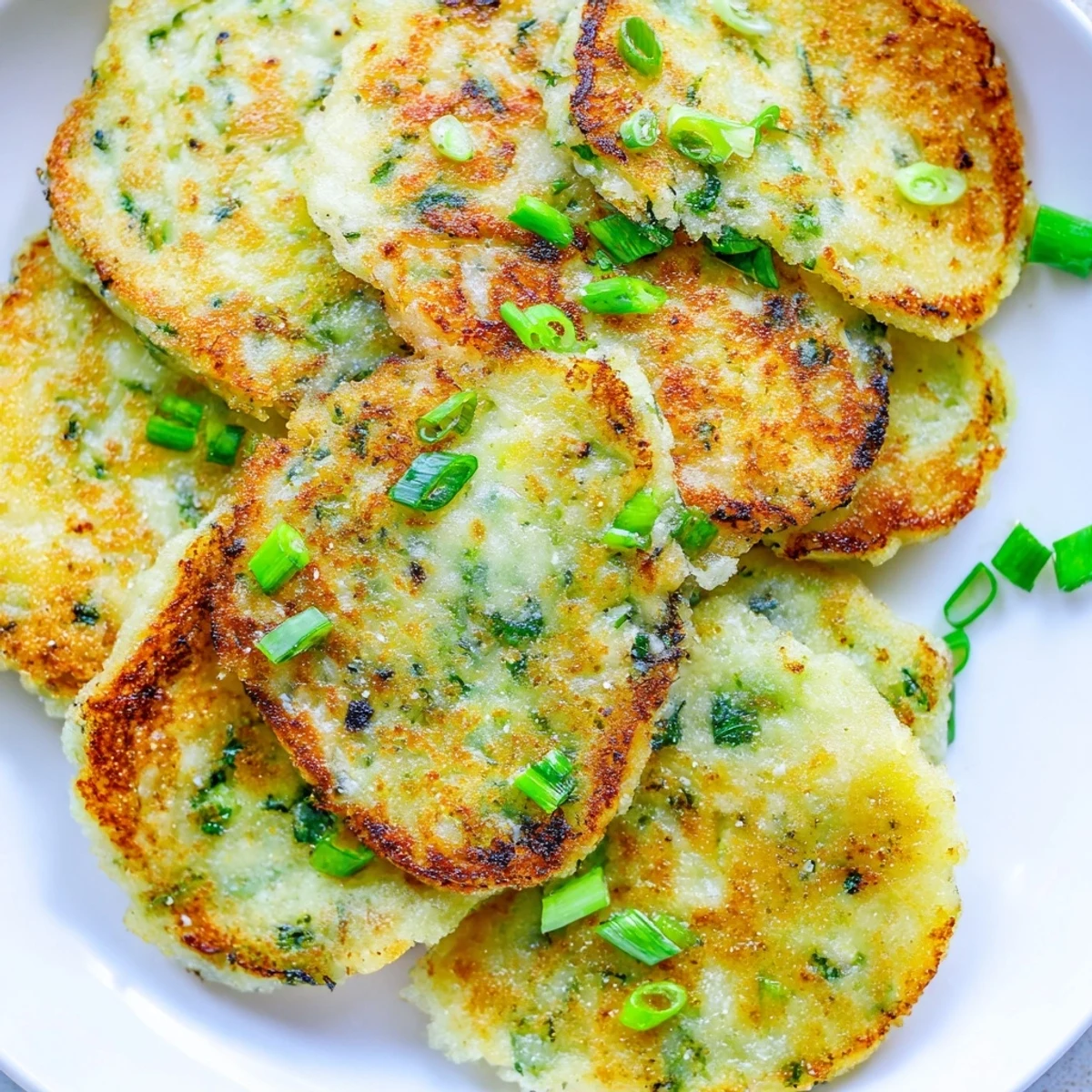 Golden-brown Irish Boxty Potato Pancakes with Scallions sizzle in a cast iron skillet, showing their crispy edges and tender centers, ready to serve for brunch.
