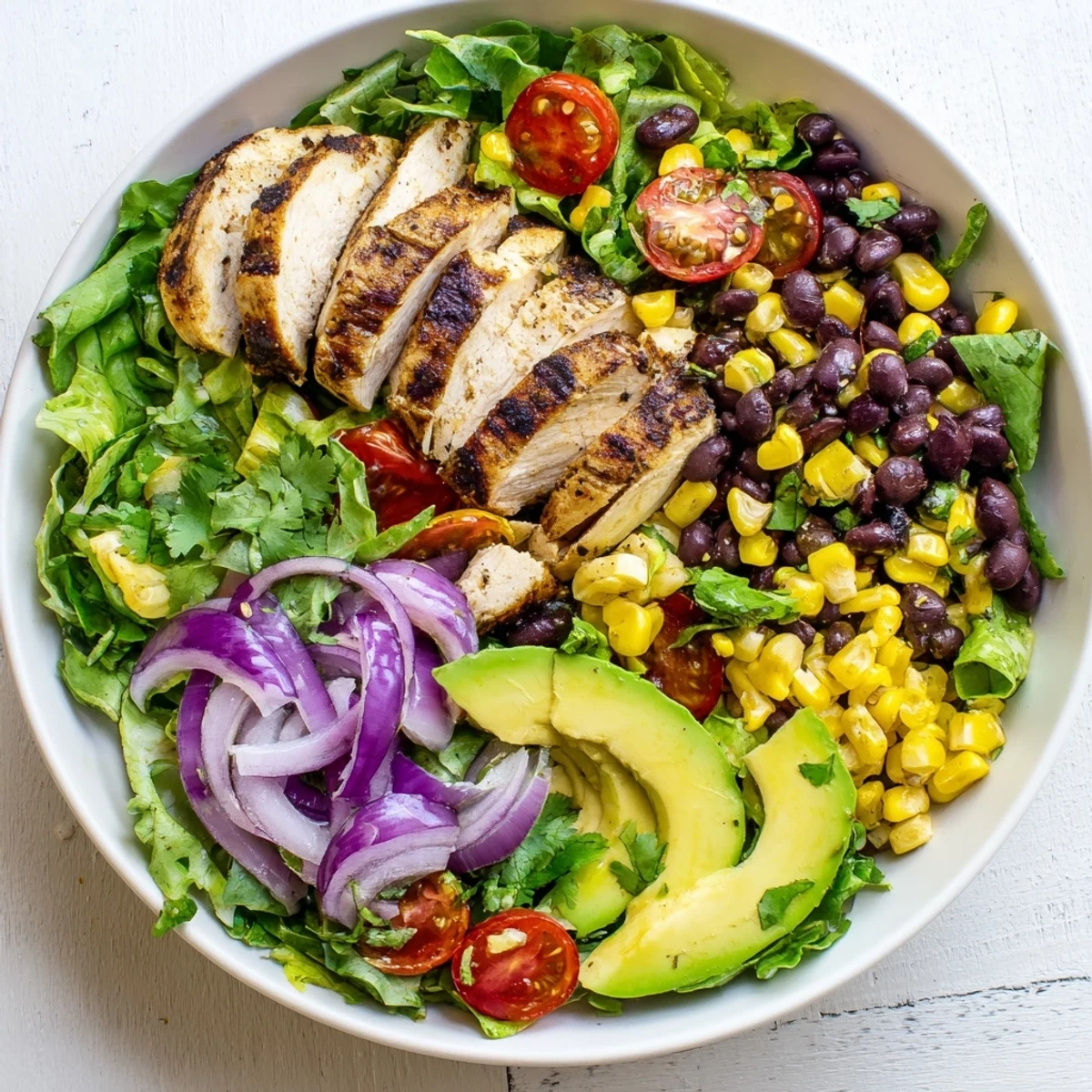 A finished plate of Chipotle Lime Chicken Salad shows juicy marinated chicken atop mixed greens with lime dressing drizzled over the top.