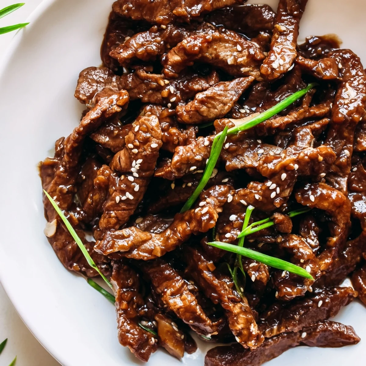 This slow-cooked Ultimate Slow Cooker Mongolian Beef is served over steamed rice with sesame seeds on a plate.