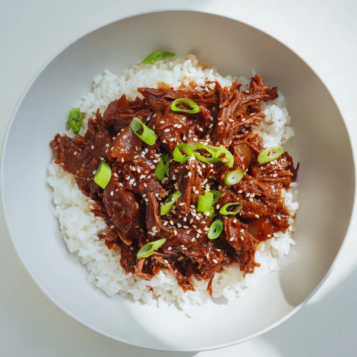 A slow cooker filled with juicy Korean beef chunks in a rich, aromatic sauce, ready to be served over fluffy white rice.