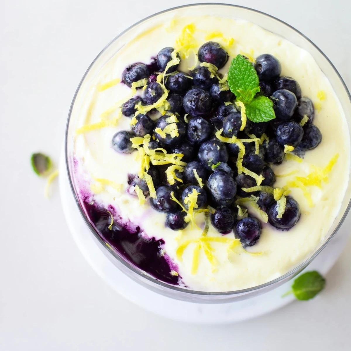 A glass of Lemon Blueberry Mousse layered with vibrant blueberry compote and smooth, tangy lemon cream, garnished with fresh berries.