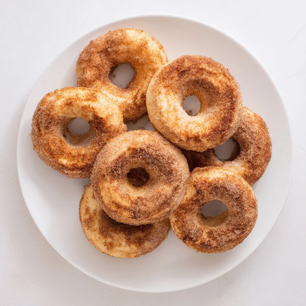A close-up of delicious Baked Cinnamon Sugar Donuts You Can't Resist, glistening with buttery sugar coating on a rustic wooden board.