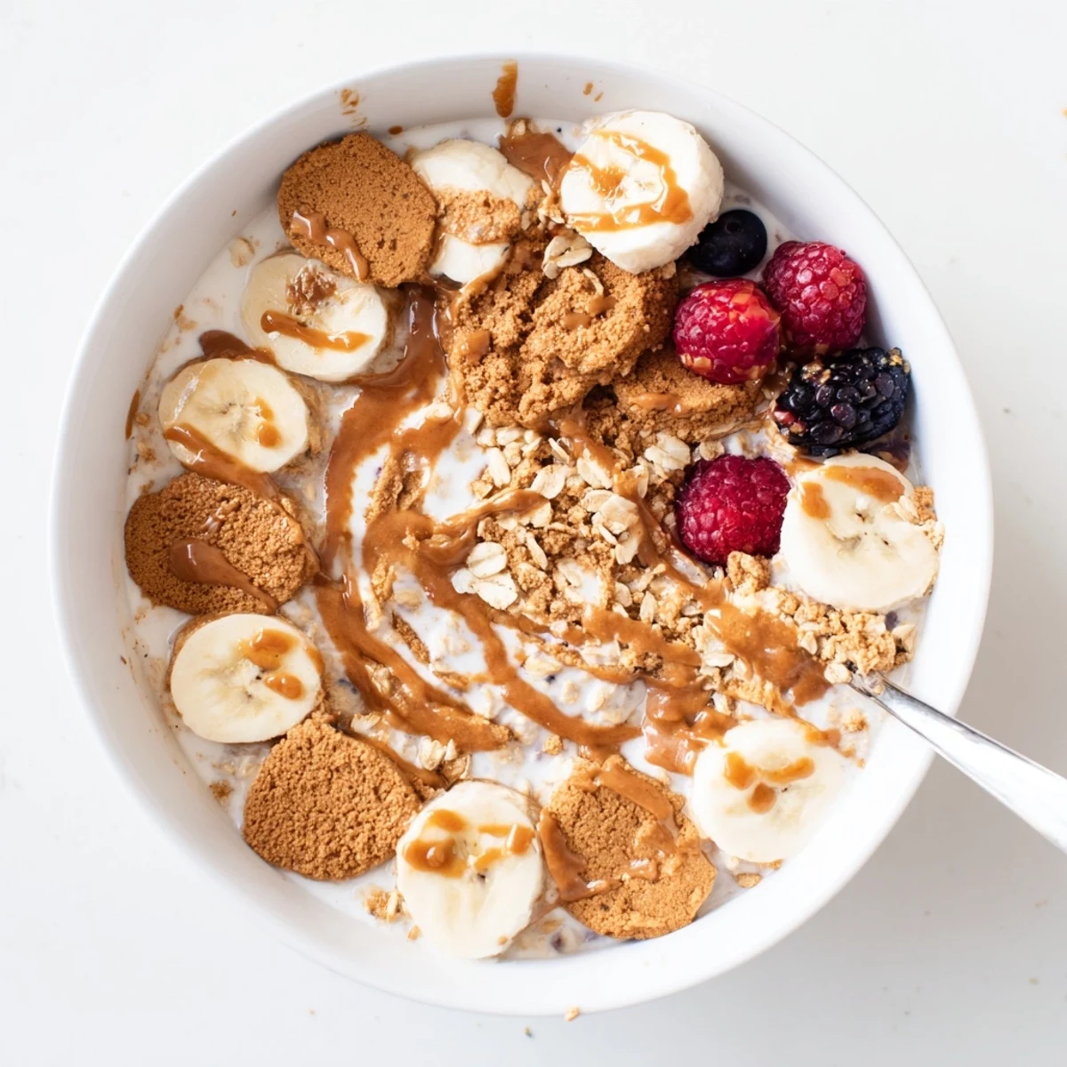 Creamy Quick Biscoff Overnight Oats topped with crushed cookies and fresh berries in a clear glass jar.