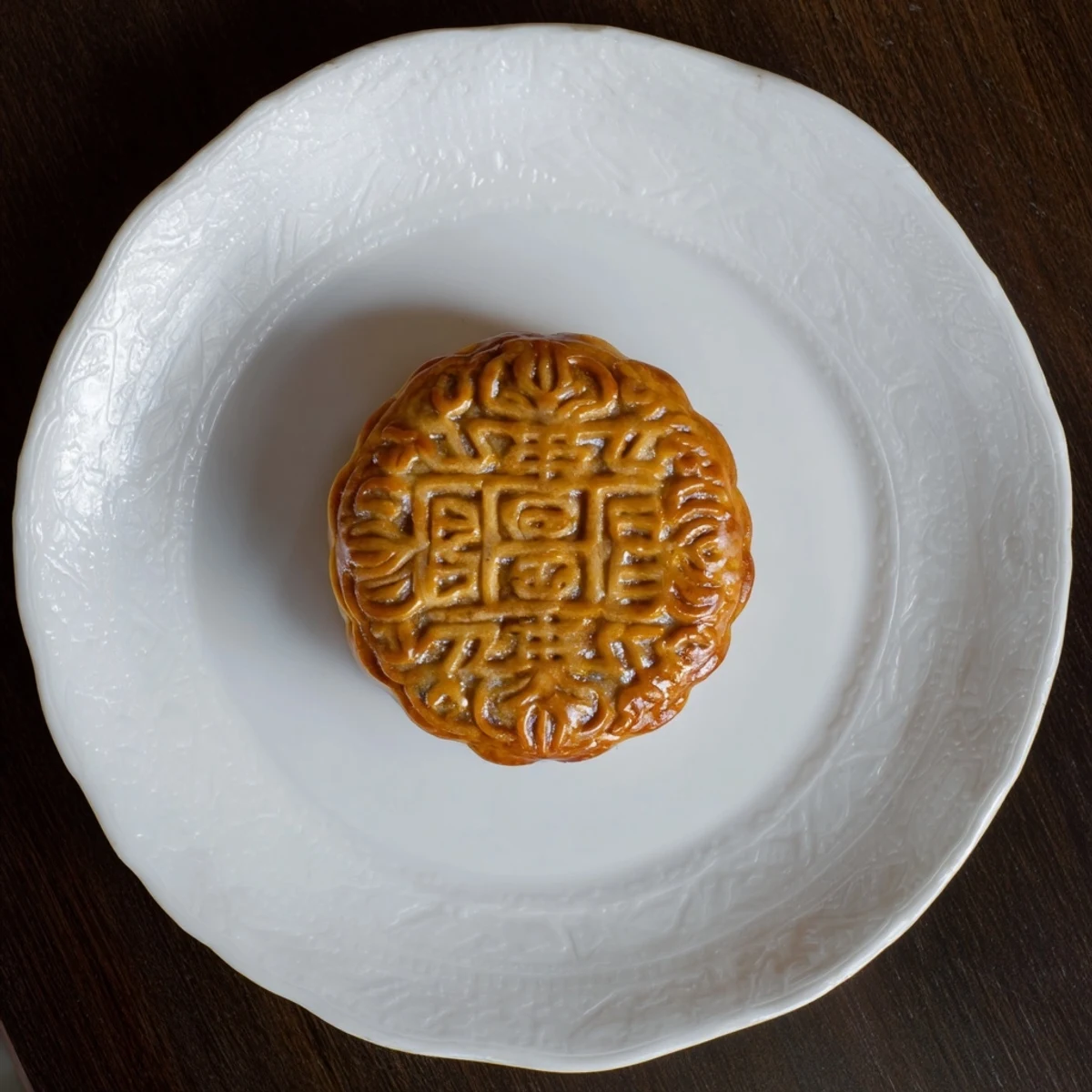 Golden baked mooncake with rich lotus seed paste displayed on a decorative plate for Mid-Autumn Festival.