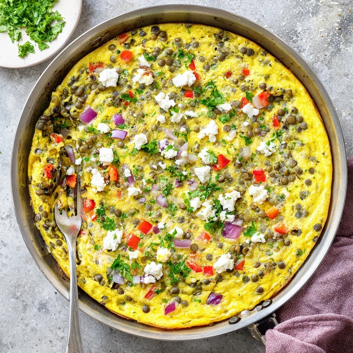 Freshly baked Healthy Lentil and Frittata with bell pepper specks and herbs rests on a rustic wooden board.
