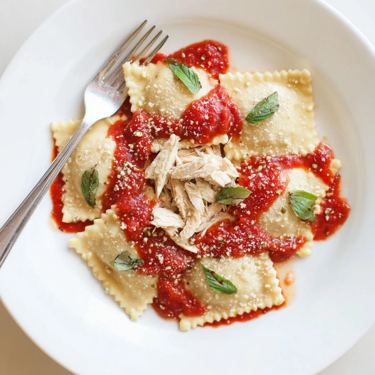 Close-up of Chicken and Mushroom Ravioli with Simple Tomato Sauce, topped with fresh basil and grated Parmesan cheese on a rustic wooden table.