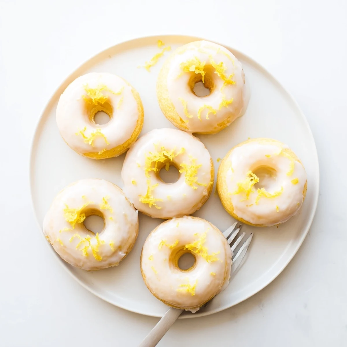 Soft lemon mochi donuts arranged on a white plate with powdered sugar dusting
