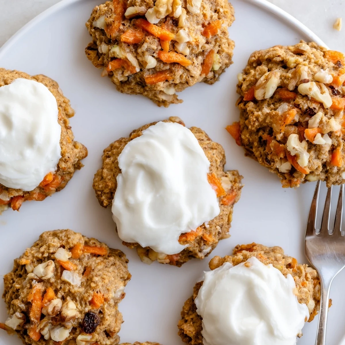 Golden-brown carrot cake cookies spread with tangy cream cheese frosting and sprinkled with walnuts