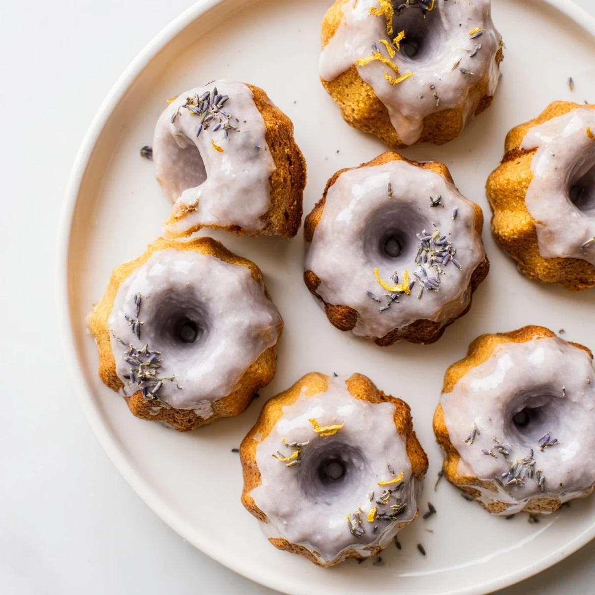 Mini lemon cakes topped with floral lavender glaze and fresh zest garnish