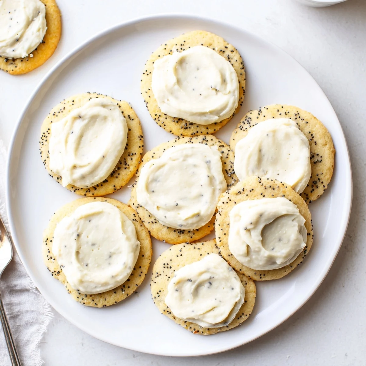 Golden lemon poppy seed cookies topped with creamy cheesecake frosting and zest
