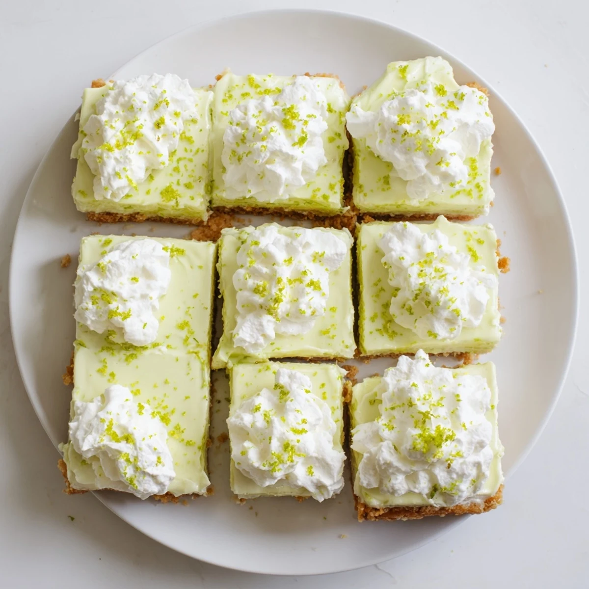 Golden Key Lime Pie Bars feature a graham craker crust topped with bright green lime filling and whipped cream