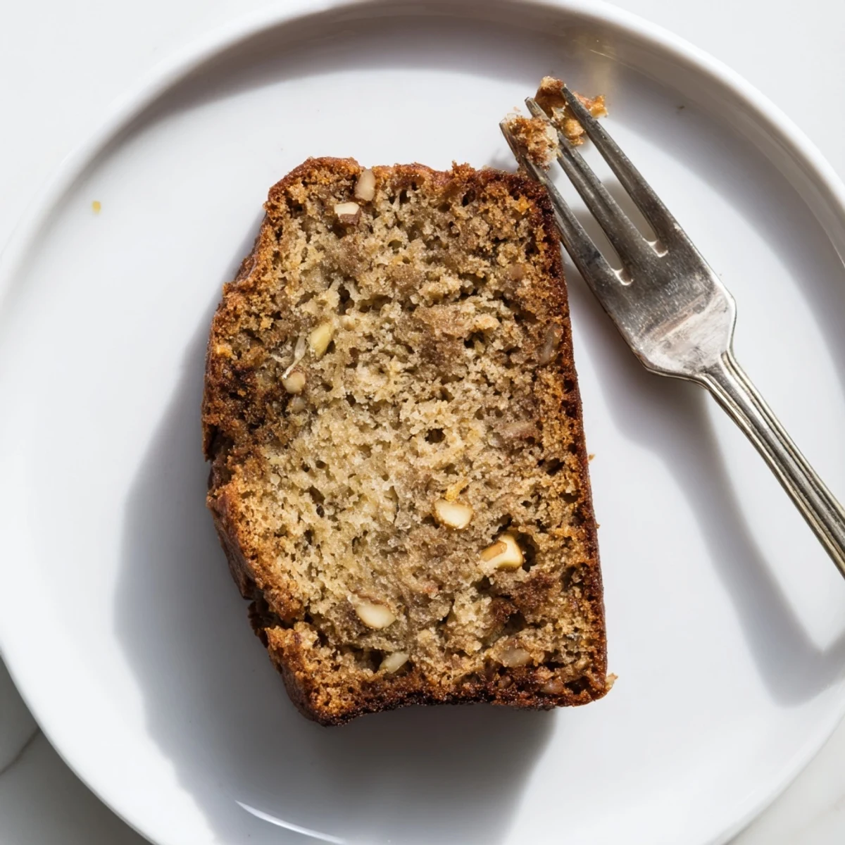 Freshly baked moist banana bread with dark specks of ripe banana, cooling on a wire rack
