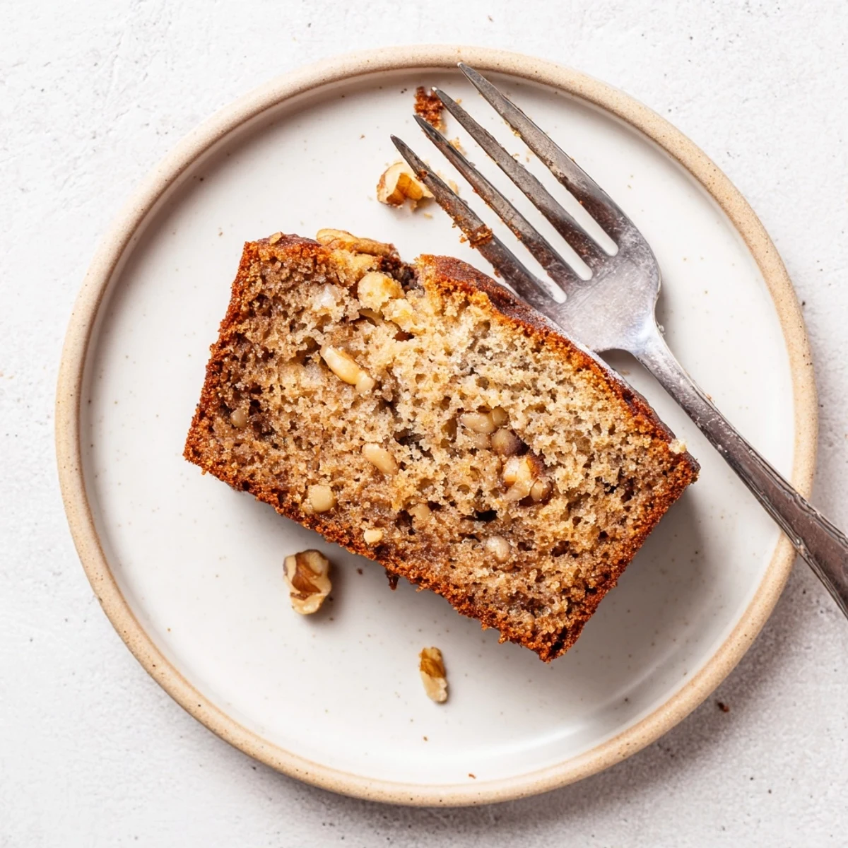 Homemade moist banana bread with a crackled golden crust, served warm with melted butter pooling on top