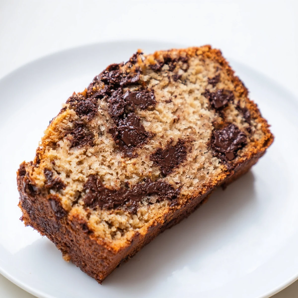 Sliced chocolate chip banana bread on a wooden board showing moist texture and chocolate pockets