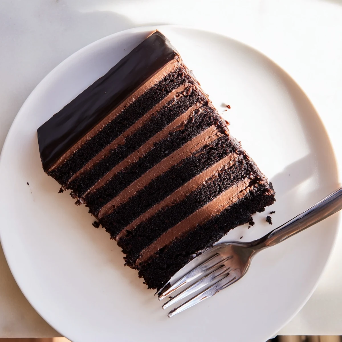 Rich dark chocolate mousse cake slice showing creamy mousse layers beneath a glossy poured chocolate glaze