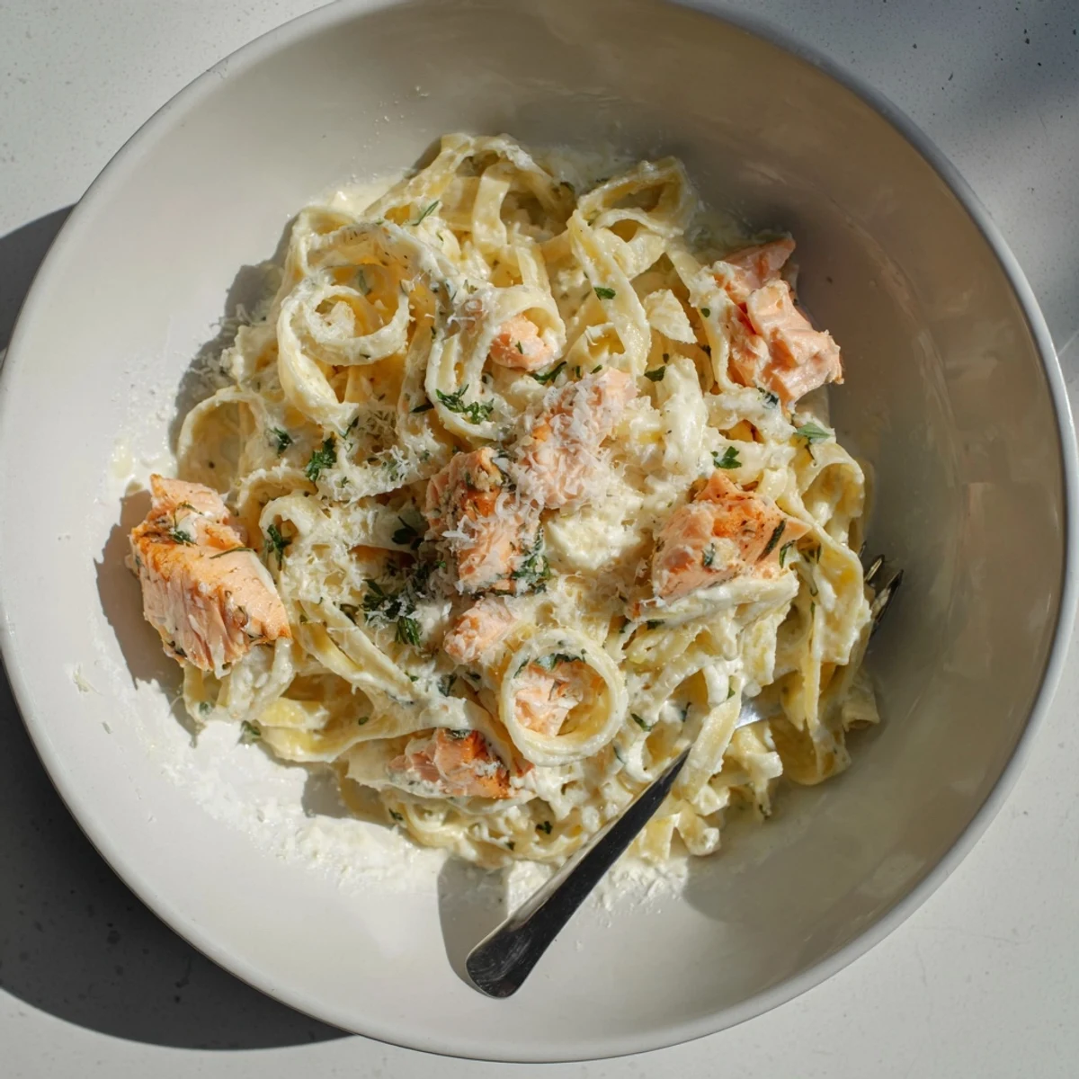 Tender fettuccine noodles coated in rich parmesan garlic cream sauce with flaked salmon