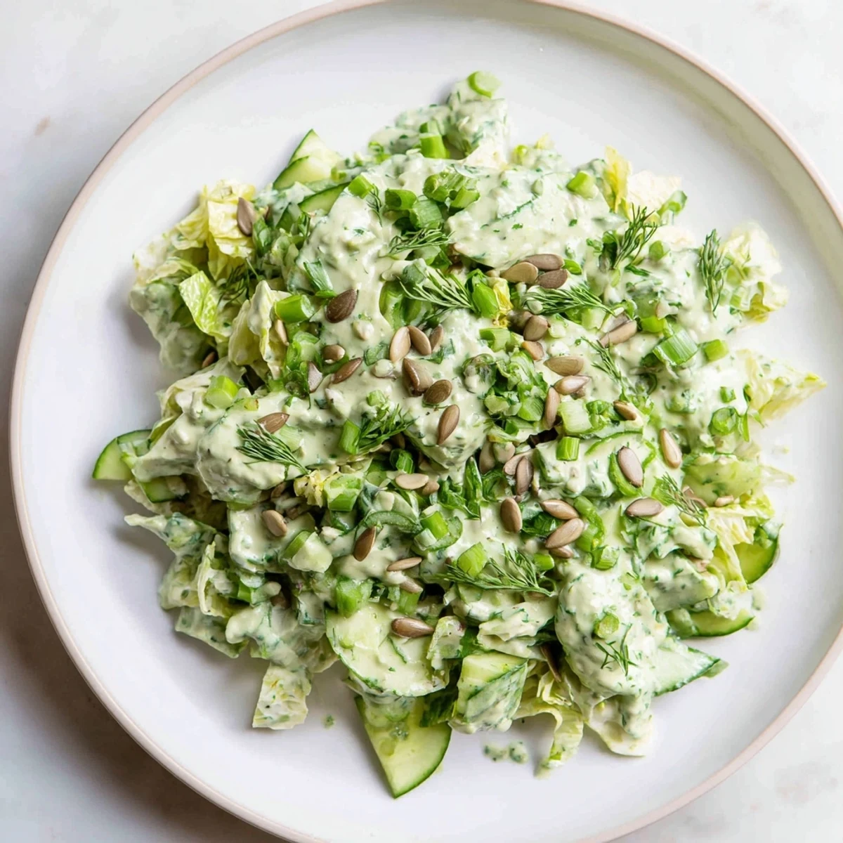 Colorful Green Goddess salad platter with green vegetables, creamy dressing, and pumpkin seed topping for a light lunch