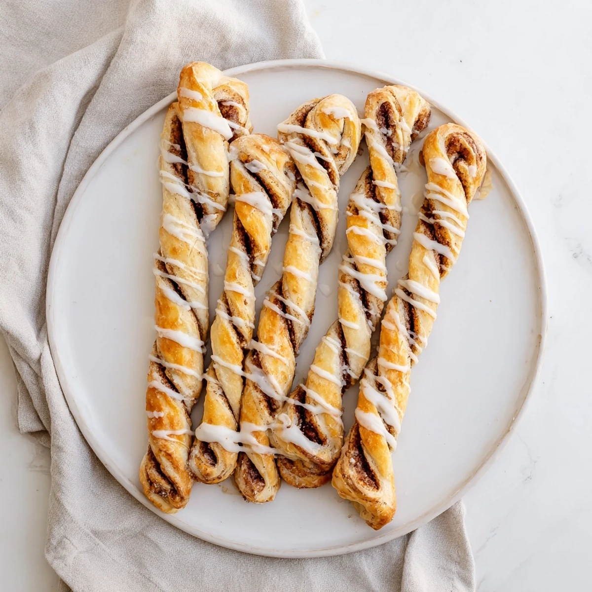 Golden sweet cinnamon twists drizzled with white vanilla glaze on a wooden board