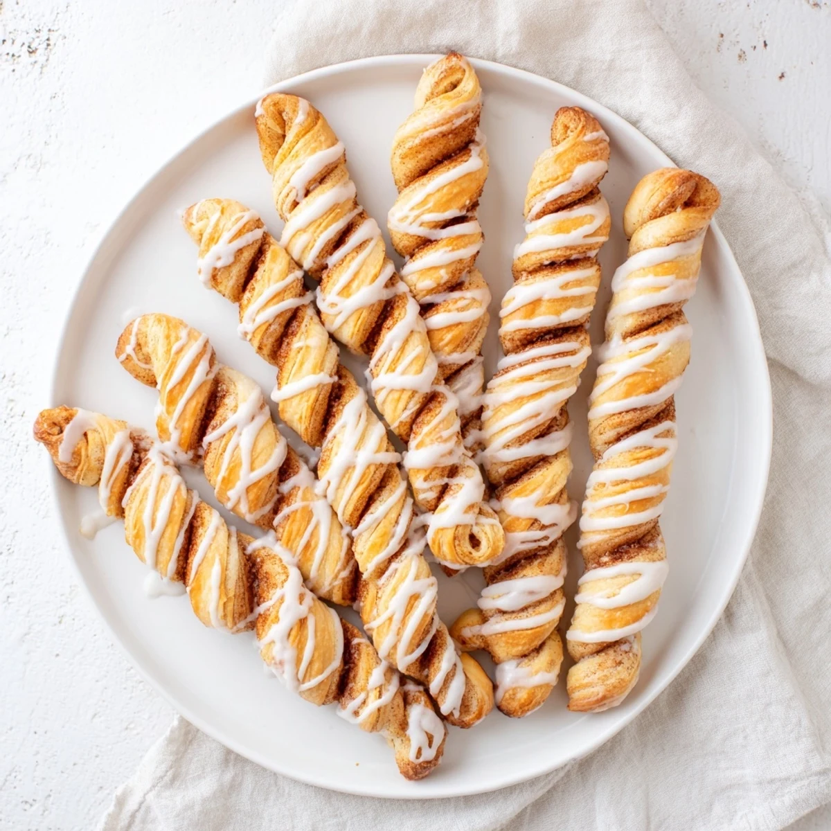 Soft baked cinnamon sugar pastry twists arranged on a white serving platter