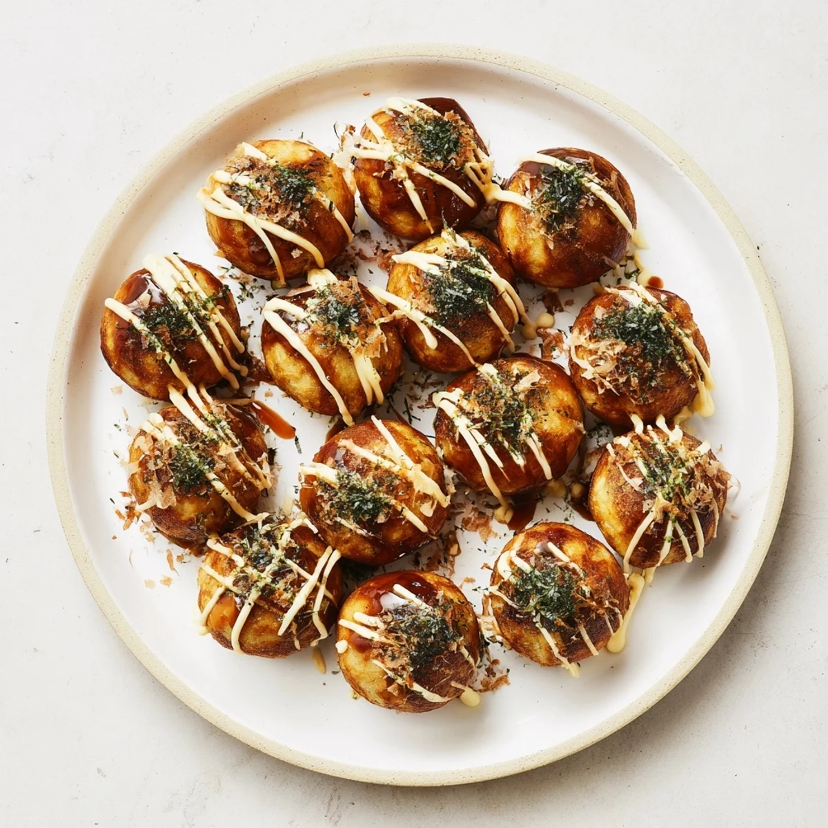 Golden brown Japanese takoyaki balls drizzled with savory sauce and mayonnaise garnished with dancing bonito flakes