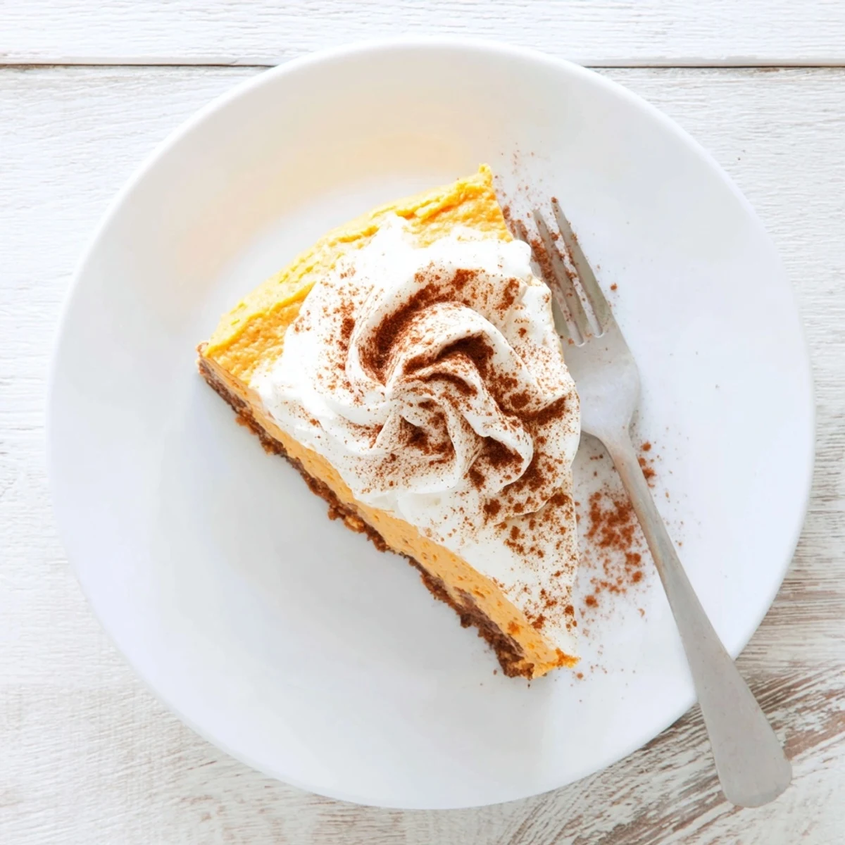 Festive Christmas dessert featuring spiced pumpkin cheesecake topped with vanilla whipped cream and dusted with cinnamon