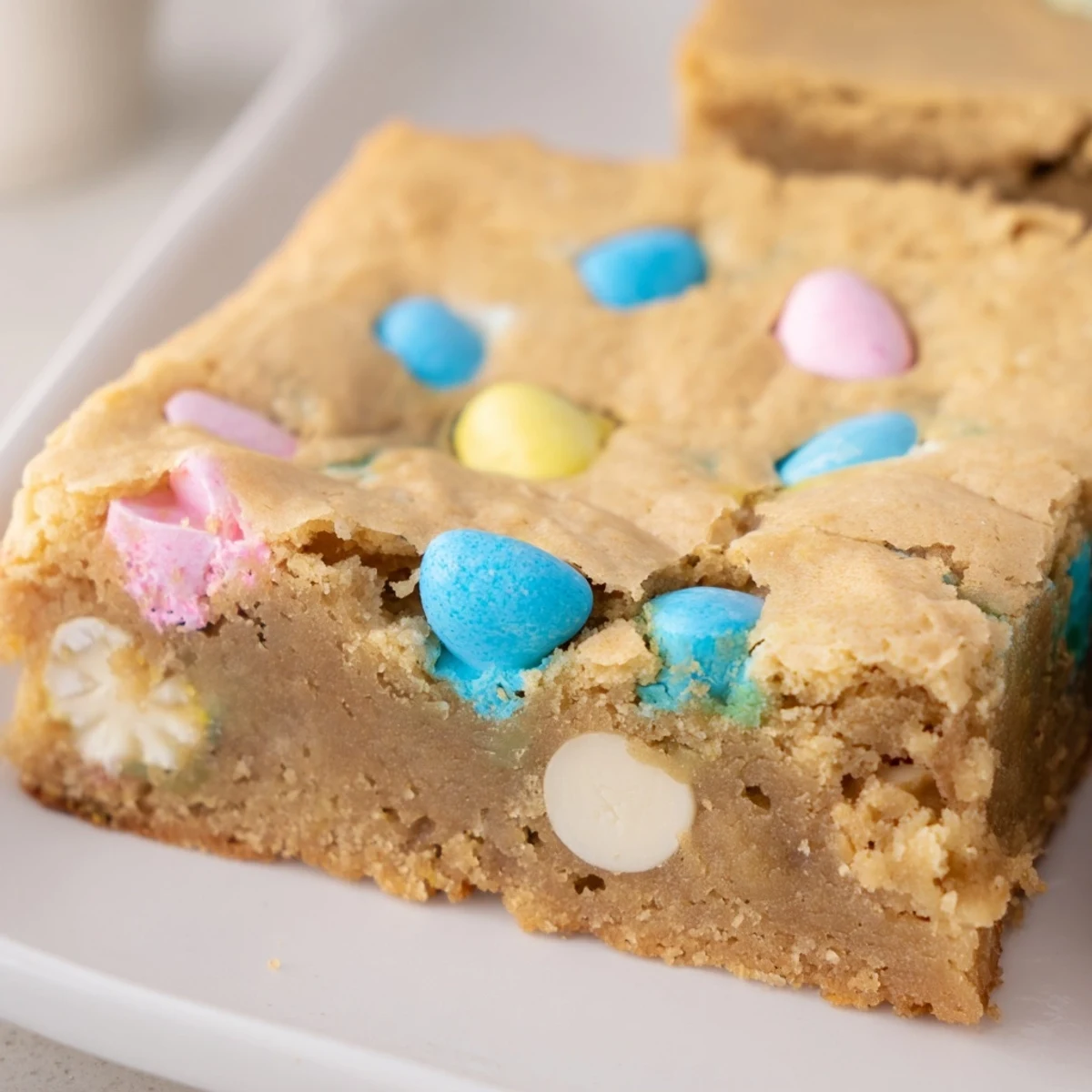 Chewy Mini Cadbury Easter Egg Blondies with colorful candy pieces scattered across golden, rich squares