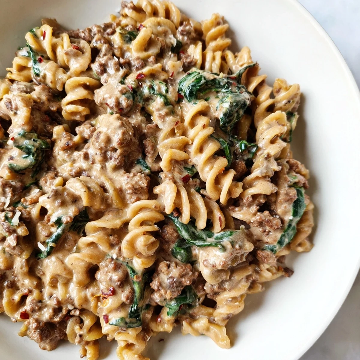 Steaming bowl of creamy high protein beef pasta garnished with fresh grated Parmesan cheese