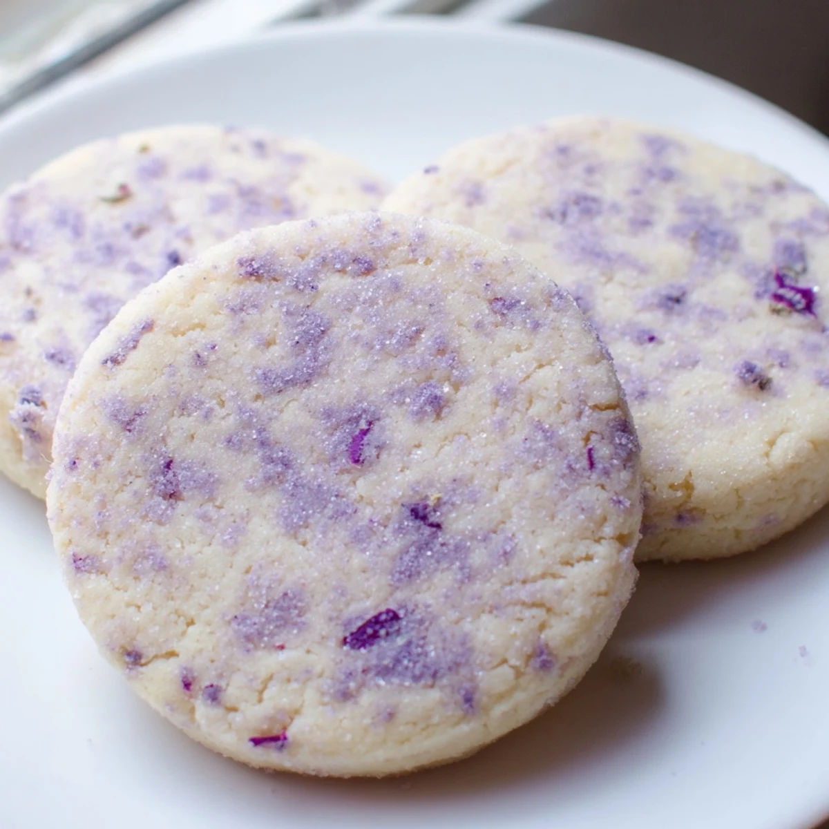 Soft lilac sugar cookies with pale purple edges on a rustic baking sheet