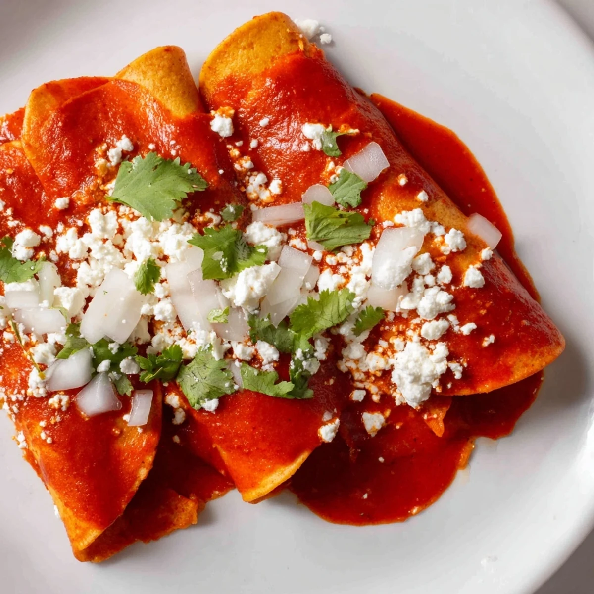 Golden entomatadas draped in rich red tomato sauce topped with crumbled queso fresco and fresh cilantro