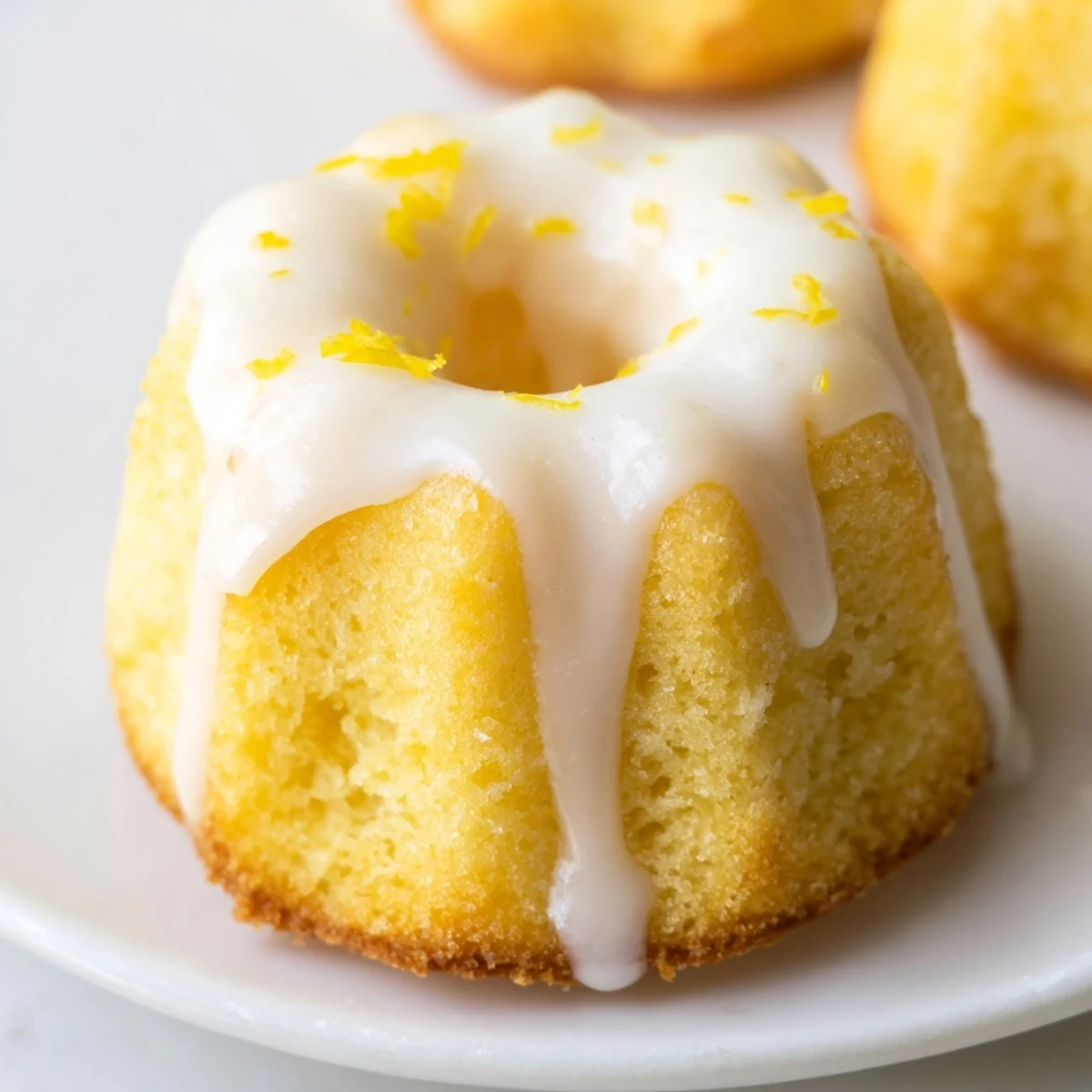 Golden mini lemon cakes drizzled with tangy glaze on a rustic wire cooling rack