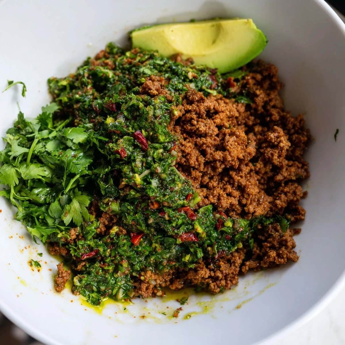 Chimichurri ground beef bowls with fresh avocado slices tomatoes and crisp cucumber garnish