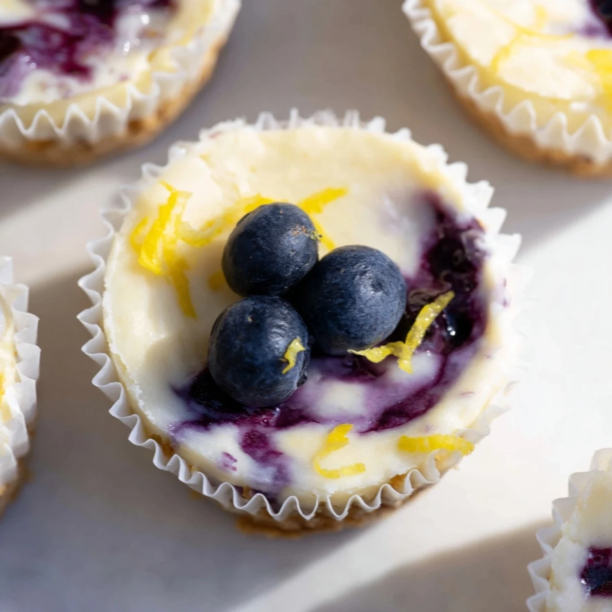 Creamy mini lemon blueberry cheesecakes with golden graham crusts and fresh berry topping