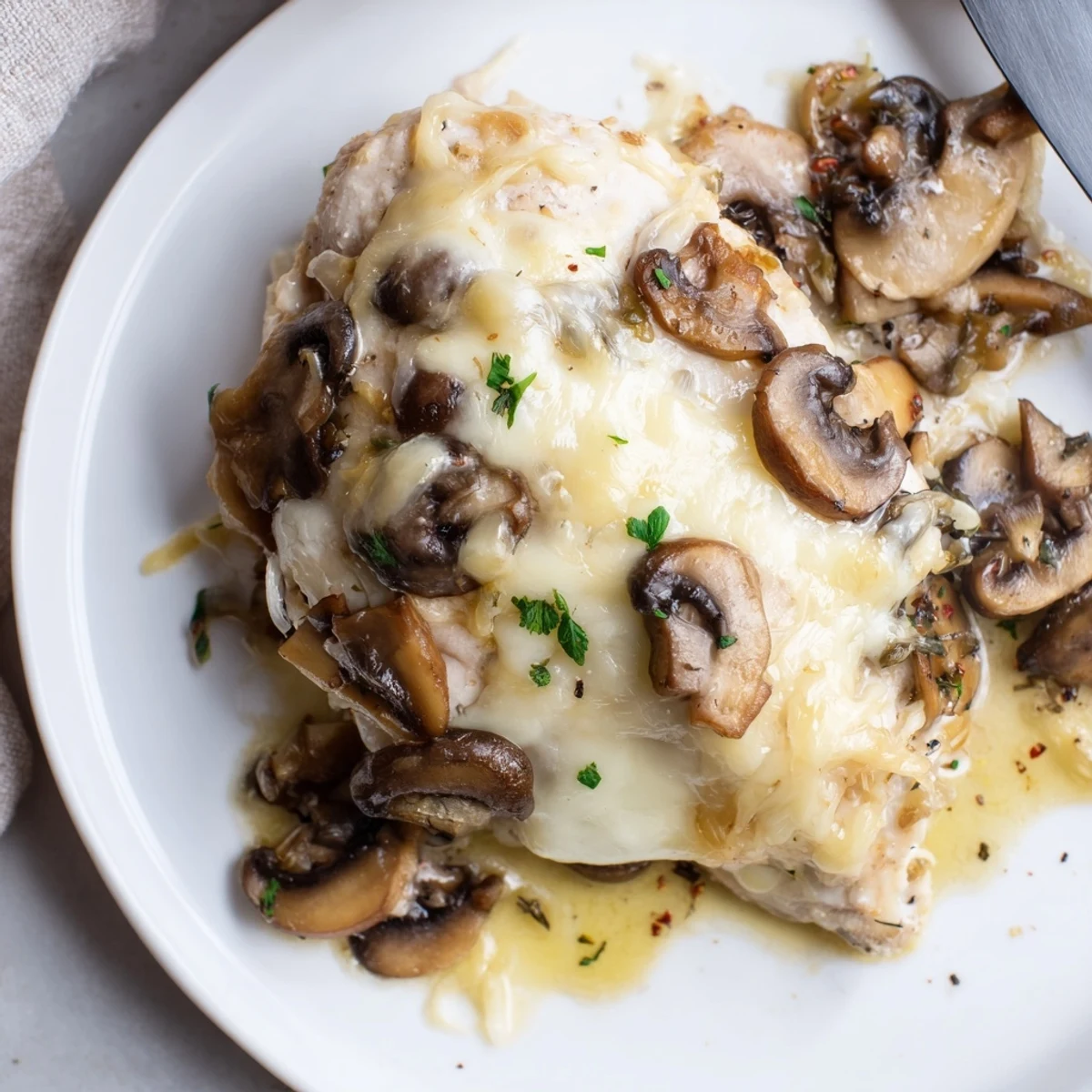 Steaming Cheesy Baked Chicken With Mushrooms served over rice, garnished with fresh thyme
