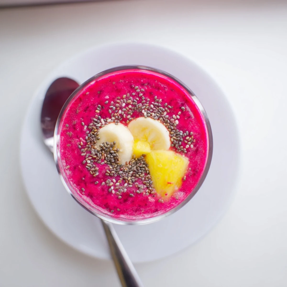Thick vibrant pink beet smoothie topped with fresh strawberries and served in a clear glass