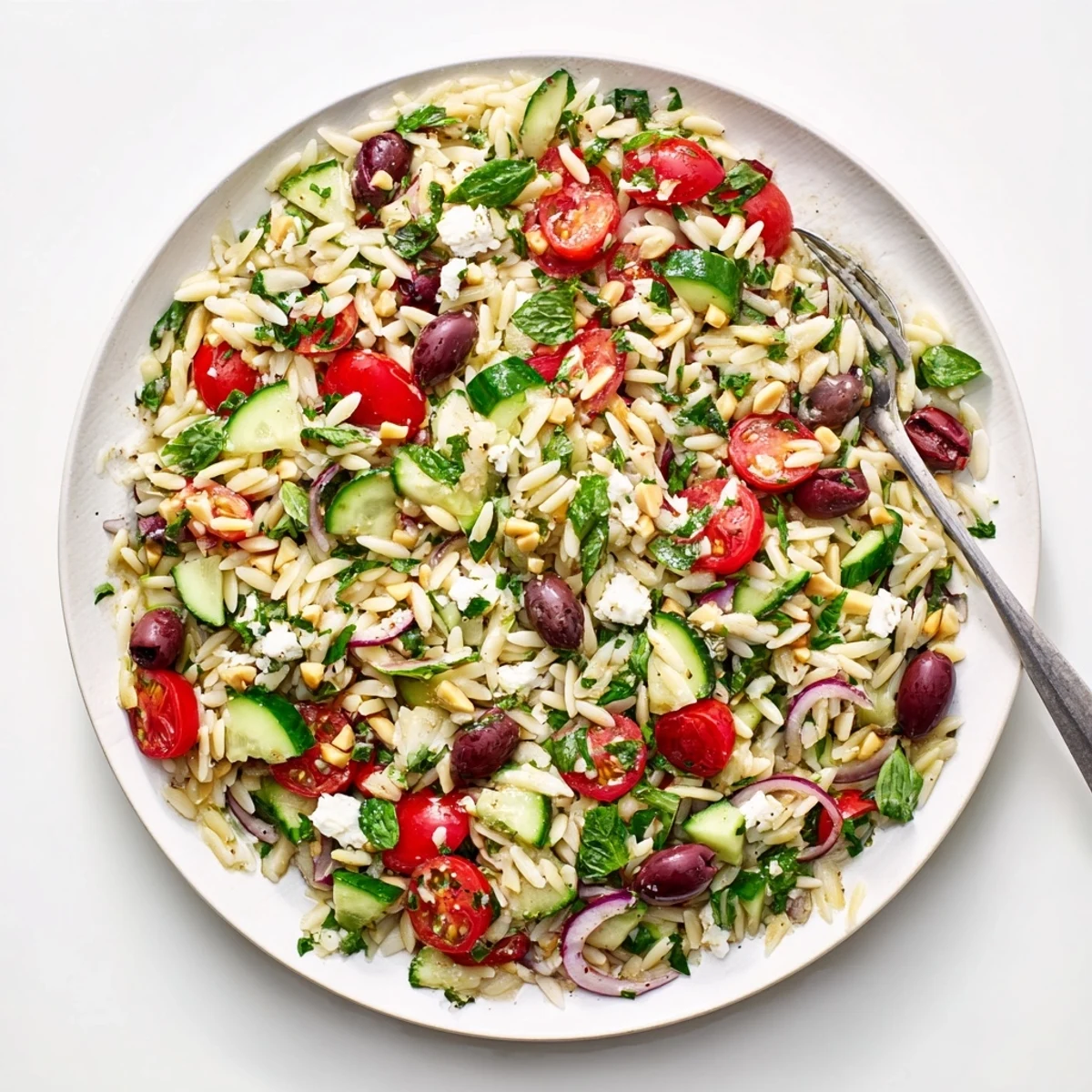 Colorful Mediterranean orzo power salad bowl topped with feta, olives, and fresh vegetables