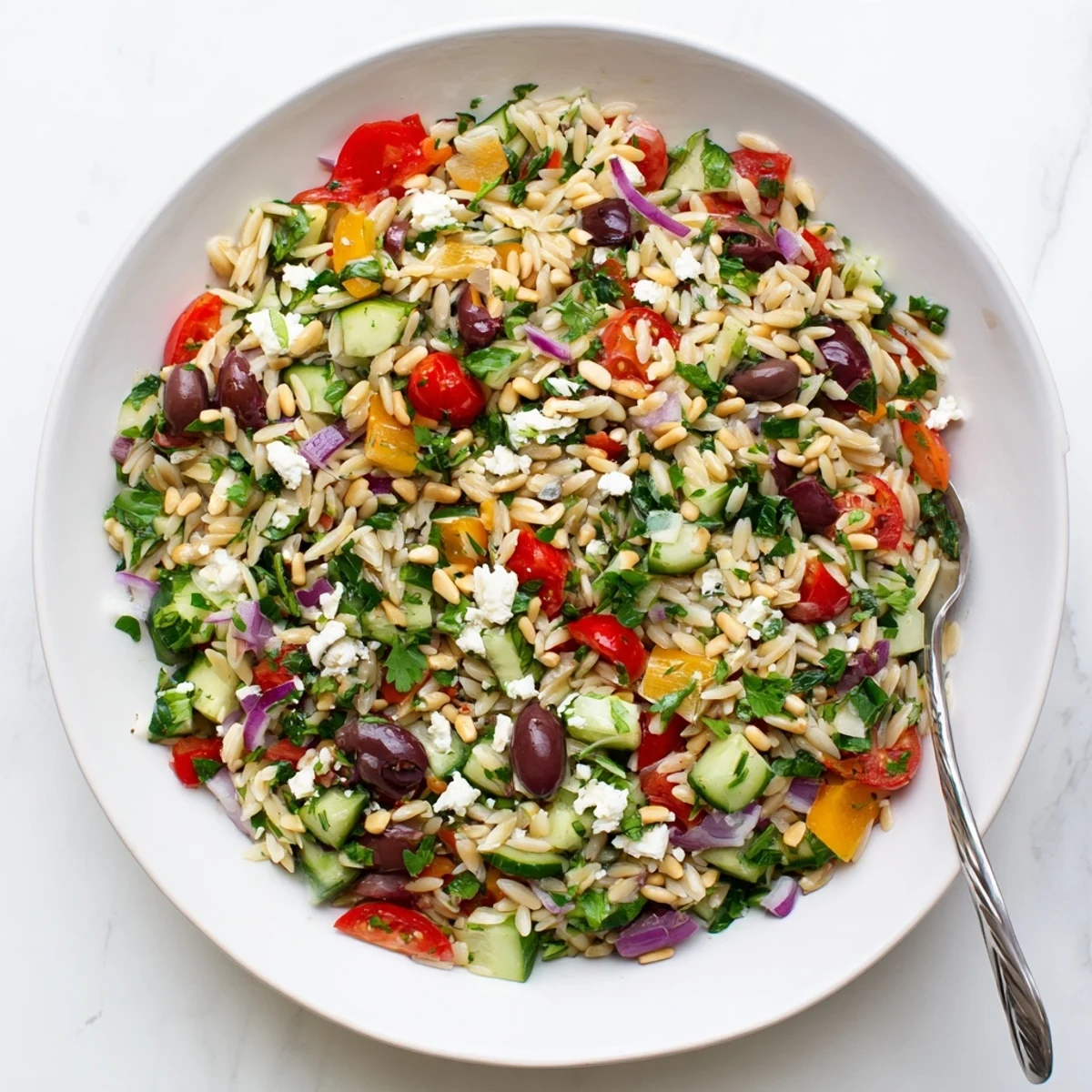 Hearty Mediterranean orzo power salad plated with crumbled feta, herbs, and pine nuts