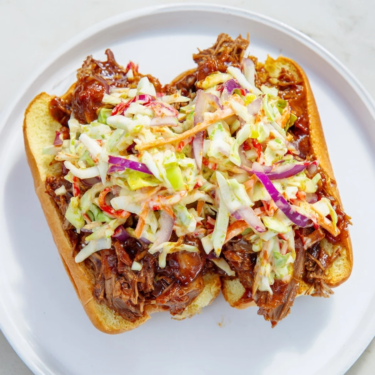 Tender smoky BBQ beef sandwiches piled high with crisp colorful coleslaw on toasted buns