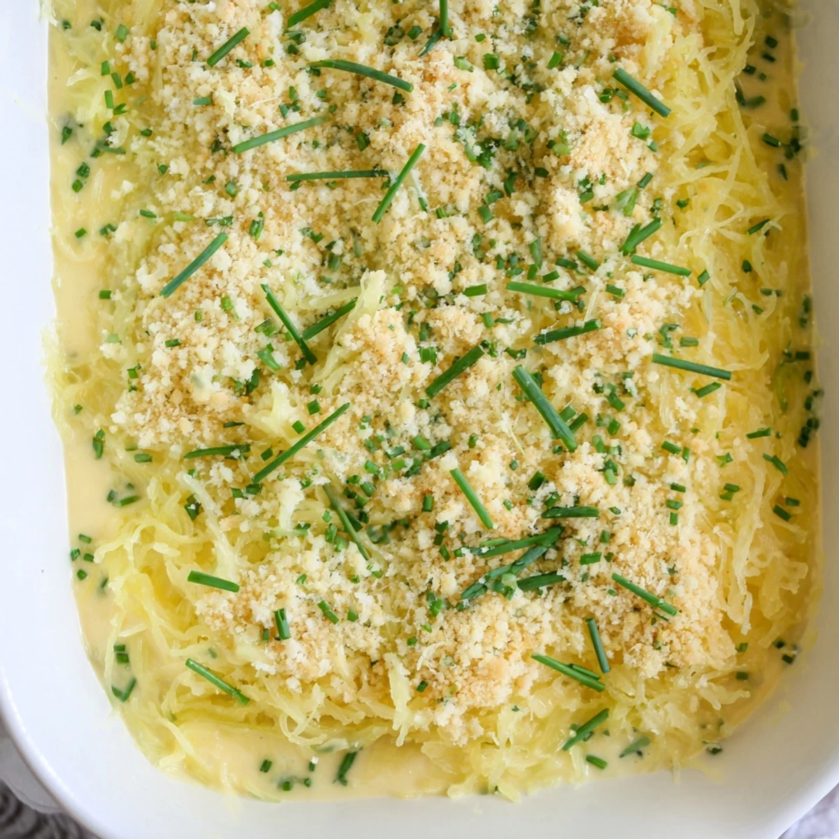 Close up of tender spaghetti squash mac cheese with golden melted cheese sauce and breadcrumb topping garnished with parsley