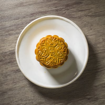 Sliced mooncake showing tender crust and sweet lotus filling, served on a bamboo tray with tea.