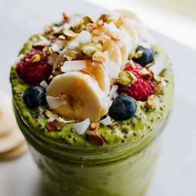 Vibrant green matcha overnight oats served in a jar with sliced banana