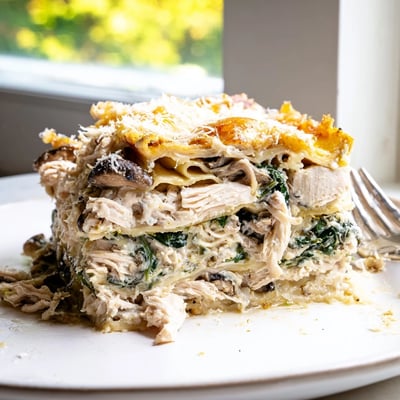 Creamy white chicken lasagna sliced to reveal tender chicken and gooey cheese layers